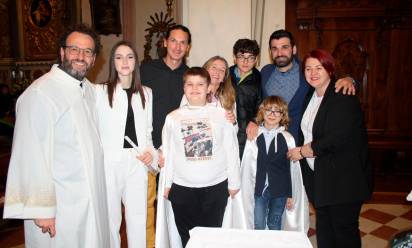 A sinistra Ethan e Matteo insieme alle loro famiglie e al parroco, don Stefano Vidotto, dopo aver ricevuto il Battesimo, durante la veglia pasquale